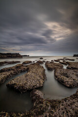 Wall Mural - Dreamy seascape for background. Beach with rocks and stones. Low tide. Blurred foggy water. Cloudy sky. Slow shutter speed. Soft focus. Copy space. Mengening beach, Bali