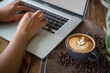 woman working with laptop computer with latte art coffee cup and coffee beans on wood table, flat design