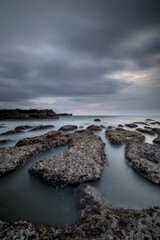 Wall Mural - Dreamy seascape for background. Beach with rocks and stones. Low tide. Blurred foggy water. Cloudy sky. Slow shutter speed. Soft focus. Copy space. Mengening beach, Bali