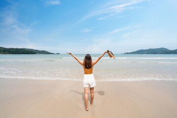 Wall Mural - Young woman traveler relaxing and enjoying at beautiful tropical white sand beach with wave foam and transparent sea, Summer vacation and Travel concept