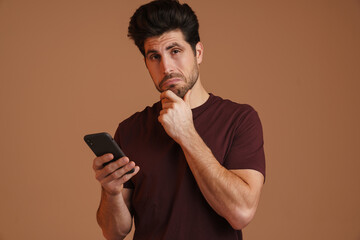 Wall Mural - Brooding masculine man using mobile phone while posing on camera