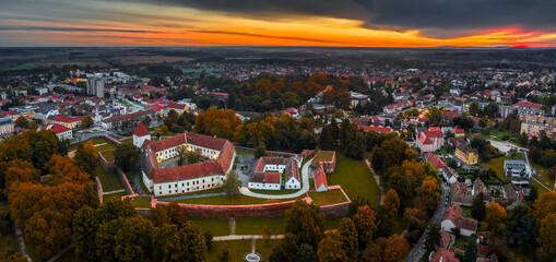 Wall Mural - Sarvar, Hungary - Aerial panoramic view of the Castle of Sarvar (Nadasdy castle) with Sarvar Arboretum, a beautiful dramatic sunrise and rain clouds at background on a calm autumn morning
