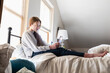 © Mint Images - Teenage girl sitting on her bed using her smart phone