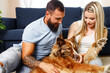 © fotofabrika - Young loving couple relaxing in living room with their dog pet