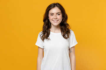 Wall Mural - Young smiling happy friendly fun eueropean caucasian student woman 20s wearing white basic casual blank print design t-shirt looking camera isolated on yellow orange color background studio portrait.