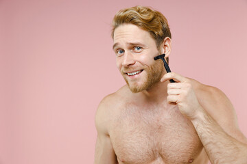 Wall Mural - Smiling attractive bearded naked young man 20s years old perfect skin shaving with plastic razor isolated on pastel pink background studio portrait. Skin care healthcare cosmetic procedures concept.