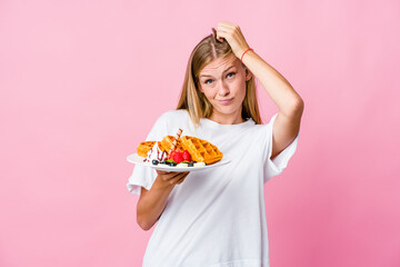 Wall Mural - Young russian woman eating a waffle isolated being shocked, she has remembered important meeting.