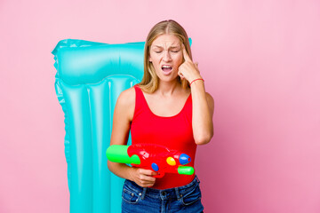 Wall Mural - Young russian woman playing with a water gun with an air mattress showing a disappointment gesture with forefinger.