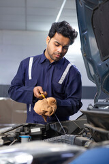 Wall Mural - A  mechanic checking motor oil during the maintenance and servicing of a car	