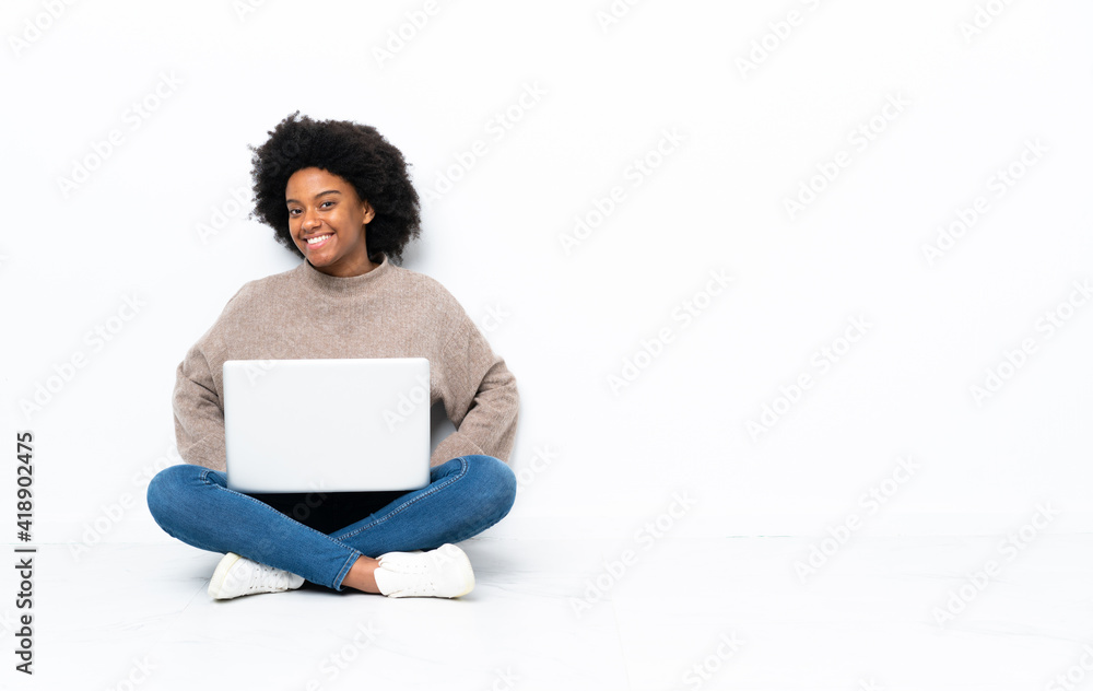 Young African American woman with a laptop sitting on the floor laughing - obrazy, fototapety, plakaty 
