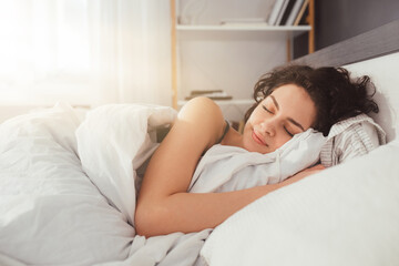 Sleepy female keeping eyes closed while sleeping at the bedroom