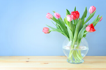 Wall Mural - spring bouquet of red and pink tulips flowers in the glass vase over wooden table