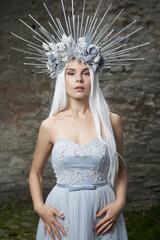 Portrait of winter queen. Attractive young woman in dress, veil, silver flower crown