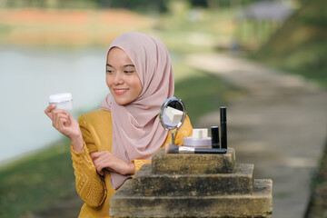 Close-up female model with hijab  applying makeup on her face. Beautiful young woman applying foundation on her face with a make up. Fashion and beauty concept