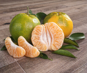 Fresh green tangerine mandarin orange on dark wooden table background.