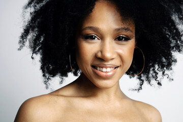 Wall Mural - close portrait of a woman smiling model of Latin American appearance. Black healthy curly hair. Clean, even skin of the face. Photo shoot in a photo studio on a white background.