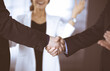 © cameravit - Businessmen are shaking hands while standing with colleagues applauding in office, close-up. Business success concept