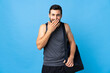 © luismolinero - Young sport man with sport bag isolated on blue background happy and smiling covering mouth with hand