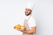 © luismolinero - Male baker holding a table with several breads isolated on white background laughing