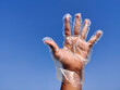 © chaundthar - South Indian Male hand wearing disposable plastic gloves. Cloud background