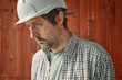 Portrait of concerned male worker with white protective helmet, employment and labor hardship concept