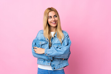 Wall Mural - Young Uruguayan blonde woman over isolated pink background looking up while smiling