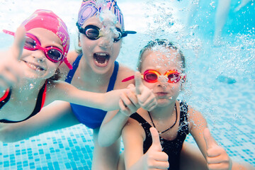 underwater photo of young friends in swimming pool.