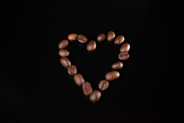 Sticker - Shape of a heart made of roasted coffee beans on a black background