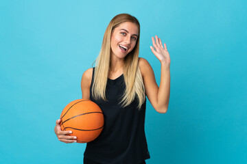 Young woman playing basketball  isolated on white background saluting with hand with happy expression