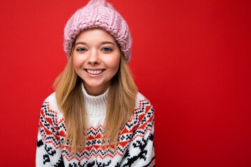 Attractive smiling happy young blonde woman standing isolated over colorful background wall wearing everyday stylish outfit showing facial emotions looking at camera