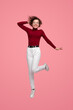 Cheerful woman in stylish clothes jumping in studio