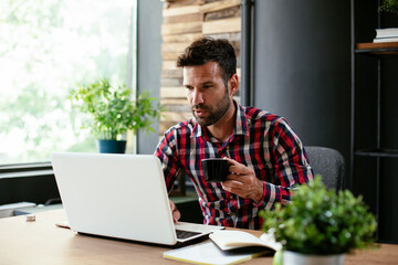 Wall Mural - Young businessman drinking coffee in his office. Businessman on coffee break.