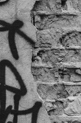 fragment of an old brick wall with the remains of graffiti on the plaster