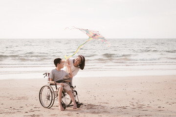 Asian special child on wheelchair playing and doing outdoor activities with parent on the beach in travel holiday, Lifestyle in the education age of disabled children, Happy disability kid concept.