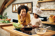 © Drazen - African American mother and daughter preparing meal in the kitchen.