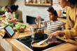 © Drazen - Small black boy and his mother using touchpad while cooking in the kitchen.