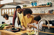 © Drazen - Happy African American family enjoying while preparing meal together in the kitchen.