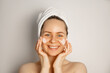 © piksik - Skin care concept.Young smiling female in towel applying face cream. Taking care of young skin concept.