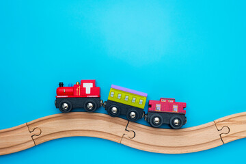 Toys background with copy space. Kids toy train with two carriages on wooden railway  on blue background with copy space for text