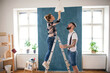 © Halfpoint - Mid adults couple changing light bulb indoors at home, relocation and diy concept.