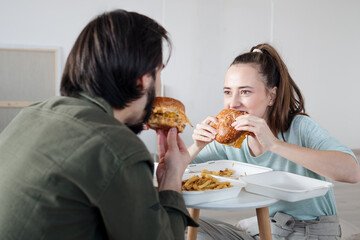 Young couple with hamburgers moving in new flat, new home and relocation concept.