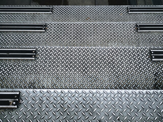 Vintage wet background of metal diamond plate in a gray silver color. Staircase, steps leading down.Top view, copy space.