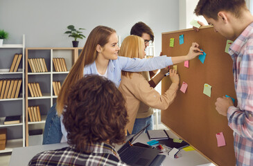 Wall Mural - College or university students working on group project. Creative schoolmates brainstorming in school library, exchanging ideas, writing them on colorful sticky notes and pinning to bulletin board