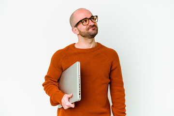 Young bald man holding a laptop isolated on white background dreaming of achieving goals and purposes