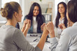 © Studio Romantic - Unity concept. Team of happy young business women holding hands with eyes closed sitting together around office table in corporate group meeting. Value, respect, support and believe in your colleagues