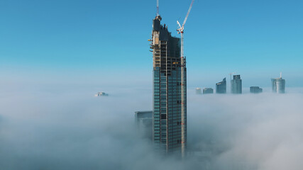 Astonishing aerial view of top of the Varso Tower under construction rising above clouds. High quality photo