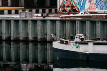A Lonely Heron Sits On A Boat On The River In The City.