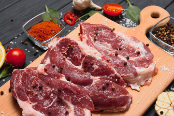 Wall Mural - Raw pork meat on wooden cutting board at kitchen table for cooking pork steak roasted or grilled with ingredients herb and spices , Fresh pork