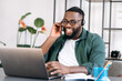© Kateryna - Distant work, supportline concept. Friendly smiling African American guy, freelancer or student, confident call center operator in a headset, uses laptop for video conference with coworkers or clients