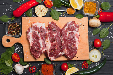 Wall Mural - Raw pork meat on wooden cutting board at kitchen table for cooking pork steak roasted or grilled with ingredients herb and spices , Fresh pork